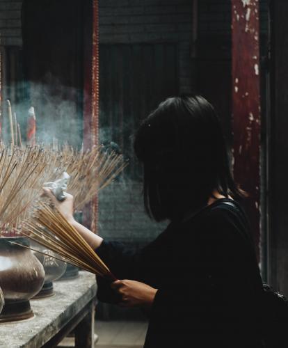 A woman lights incense at a shrine