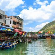 Fishing boats docked up by covered jetties alongside colourful houses